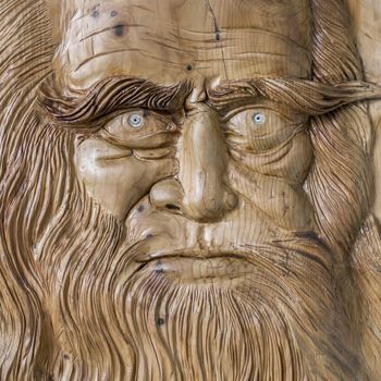 Close up of the face of Leonardo da Vinci, carved on a wooden board.
