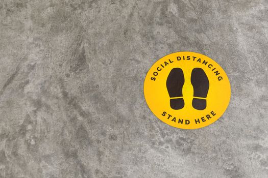 footprint sign for stand in shopping mall, supermarket. Social distancing , COVID-19 comcept. Ccoronavirus crisis. yellow footprint sign with text caution social distance.