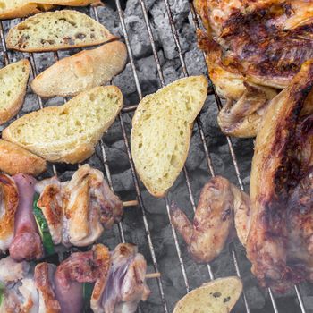 Skewer chicken pieces, half cockerel and slices of bread on the grill and smoke.
