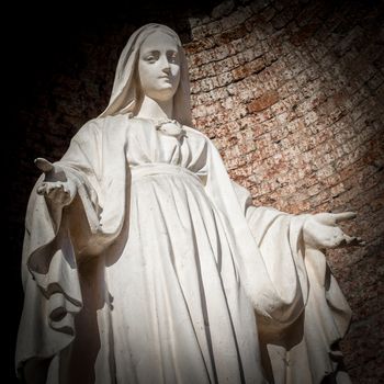 Statue of Virgin Mary in Roman Catholic Church on wall background.