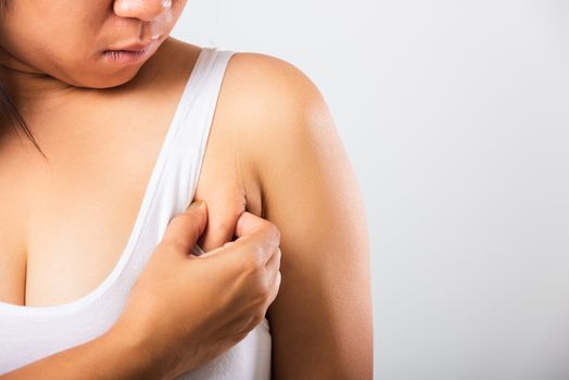 Close up of Asian woman pulling excess fat on her skin underarm she problem armpit fat underarm wrinkled skin, studio isolated on white background, Healthy overweight excess body concept