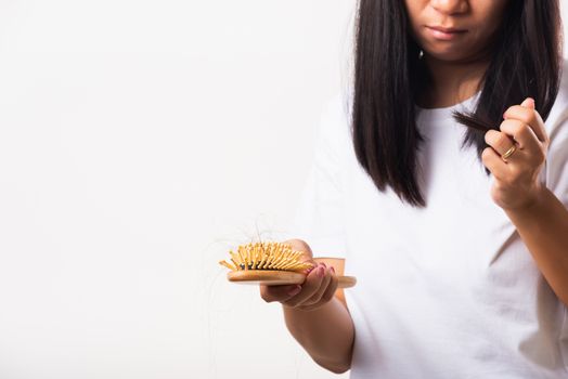 Asian woman unhappy weak hair her hold hairbrush with damaged long loss hair in the comb brush on hand and she looking to hair, studio shot isolated on white background, medicine health care concept