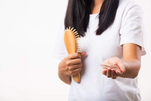 Asian woman unhappy weak hair problem her hold a hairbrush and she showing damaged long loss hair from the brush on hand, isolated on white background, Medicine health care concept