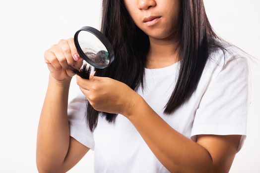 Asian woman unhappy weak hair problem her looking at destroyed hair with magnifying glass she damaged long loss hair on hand, isolated on white background, Medicine health care concept