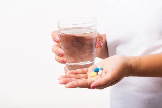 Closeup young Asian woman hold pill drugs in hand ready take medicines with a glass of water, studio shot isolated on white background, Healthcare and medical pharmacy concept