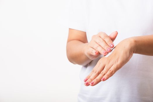 Closeup young Asian woman applying lotion cosmetic moisturizer cream on her behind the palm skin hand, studio shot isolated on white background, Healthcare medical and hygiene skin body care concept