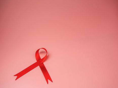 Red ribbon on pink background. world aids day concept, symbol of human immunodeficiency virus disease.