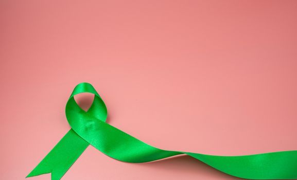 Green ribbon symbol on a pink background