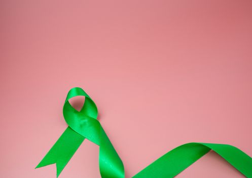 Green ribbon symbol on a pink background