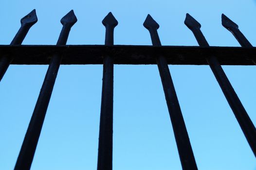 fragment of a forged fence against the background of the clear sky, bottom view