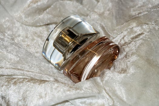 perfume bottle on white shiny cloth close-up