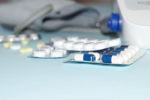 tonometer and pills close-up on blue background, copy space