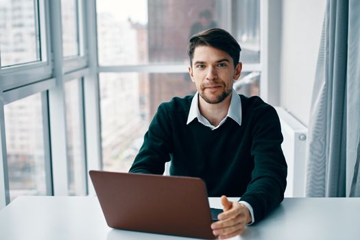 Handsome man with laptop in office near the window