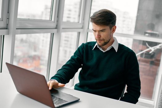 Confident businessman is typing on laptop in office room