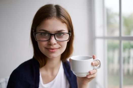 Cheerful woman at home with a cup of drink glasses lifestyle interior Comfort and relaxation morning leisure