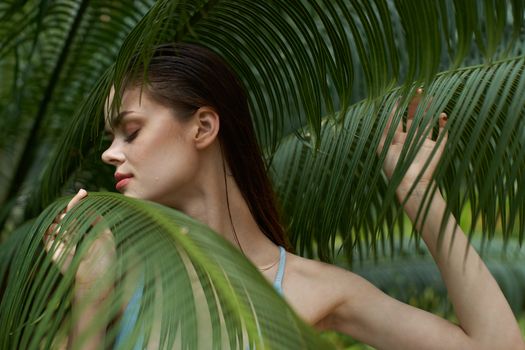 Charming woman near green leaves of bushes cropped view