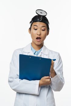 Professional female doctor with a medical tool on her head writes document information