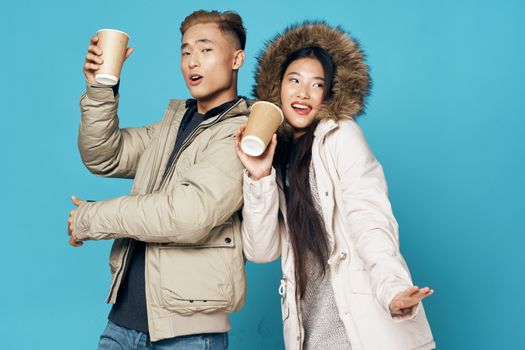 Young people have fun on a blue background with a cup of coffee in their hands
