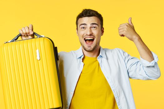 happy guy goes on a trip positive gesture and yellow suitcase