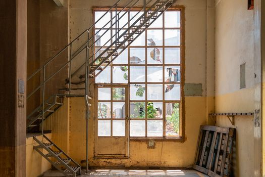 Old broken windows. with metal stairs inside a yellow building. Abandoned space