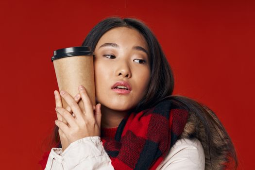 Beautiful woman on a red background hugs a cup of coffee cropped view