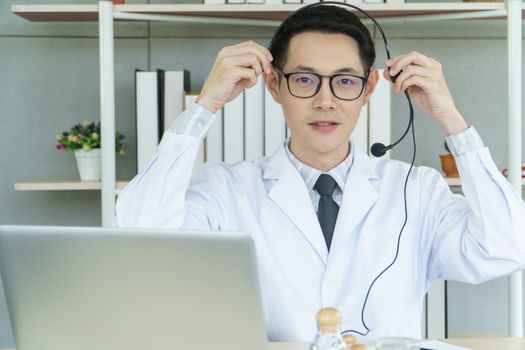 Asian male doctor is using a laptop computer to connect to the internet for online counseling. The medical profession, technology, communication, distance, and people concept