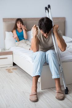 Young wife supporting husband on crutch after injury