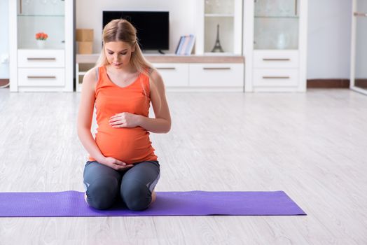 Pregnant woman doing sport exercise at home