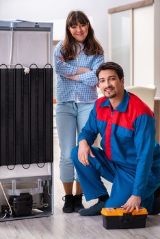Man repairing fridge with customer