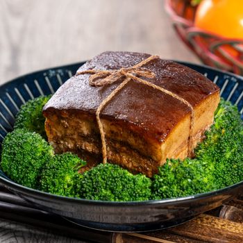 Dong Po Rou (Dongpo pork meat) in a beautiful blue plate with green broccoli vegetable, traditional festive food for Chinese new year cuisine meal, close up.