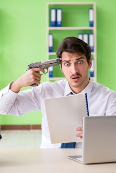 Despaired businessman thinking of suicide in the office 