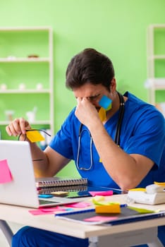 Young doctor sitting in hospital with many conflicting priorities  