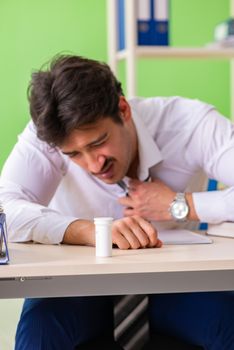 Sick and unhappy businessman sitting in the office 
