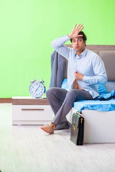 Employee in the bedroom being late for his job in time management concept