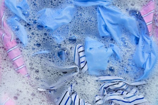Top view of color clothes soak in powder detergent water dissolution. Laundry concept