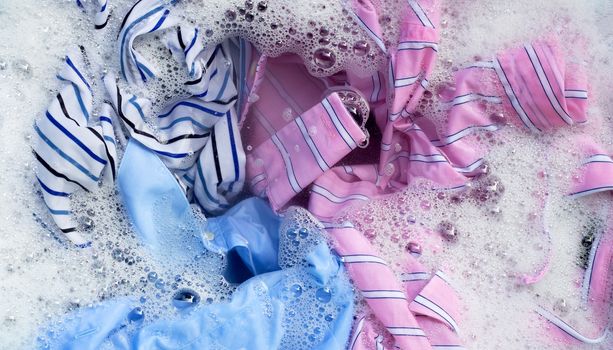 Top view of color clothes soak in powder detergent water dissolution. Laundry concept