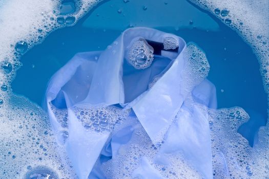 Shirt soak in powder detergent water dissolution, washing cloth. Laundry concept. Top view