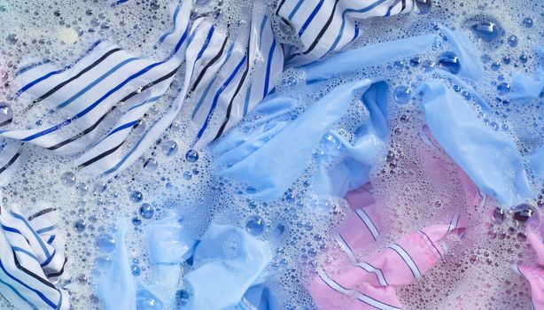 Top view of color clothes soak in powder detergent water dissolution. Laundry concept
