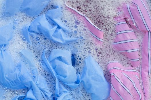 Top view of color clothes soak in powder detergent water dissolution. Laundry concept