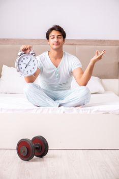 Young man doing yoga in bedroom in time management concept