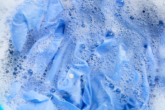 Top view of color clothes soak in powder detergent water dissolution. Laundry concept