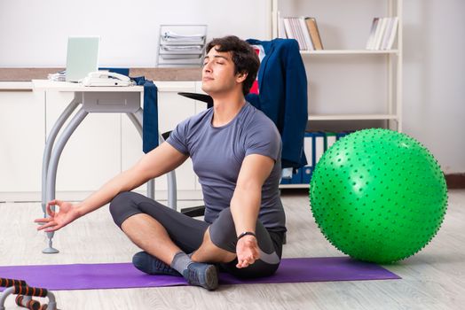 Young male employee exercising in the office