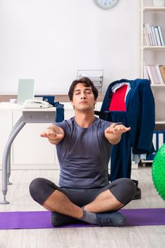 Young male employee exercising in the office