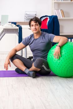 Young male employee exercising in the office