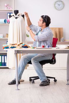 Young handsome tailor working in his workshop
