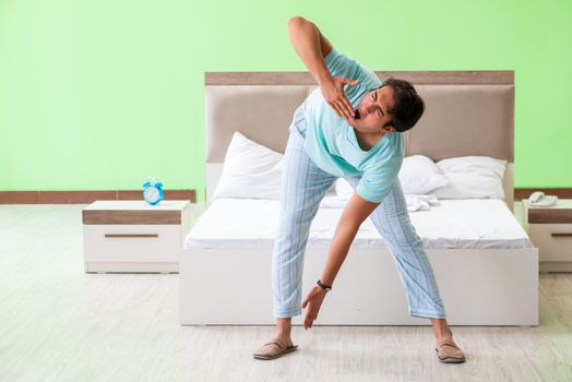 Young man in pajamas doing morning exercises 