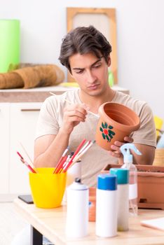 Young man decorating pottery in class