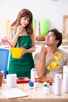 Couple decorating pots in workshop during class