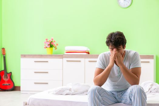 Young man having trouble waking up in early morning