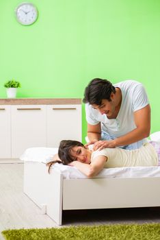 Man doing massage to his wife in bedroom 